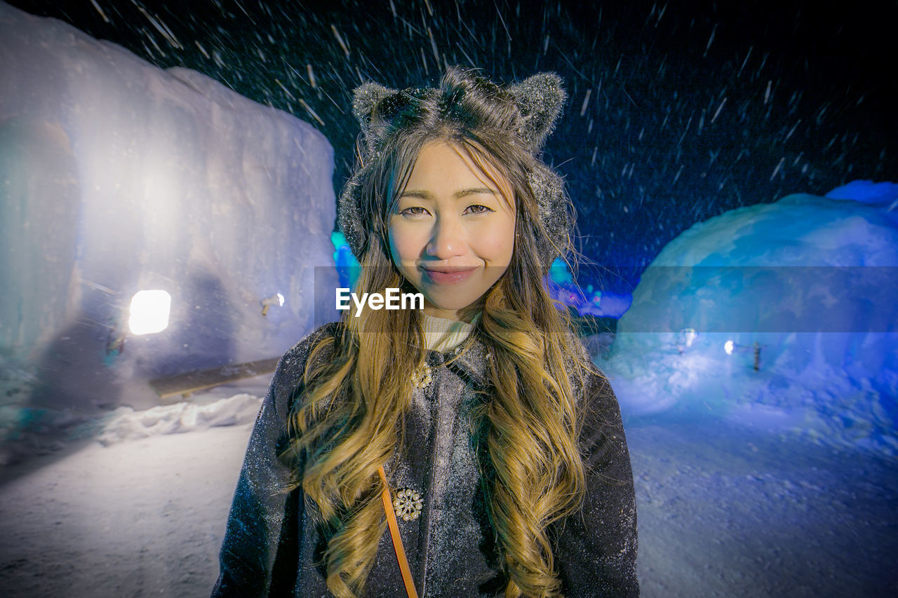 Portrait of smiling young woman standing in snow