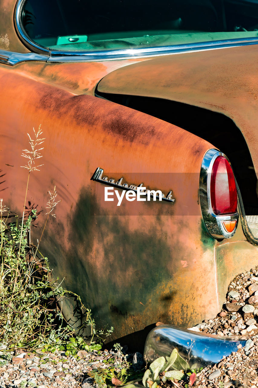 Close-up of abandoned car parked in field