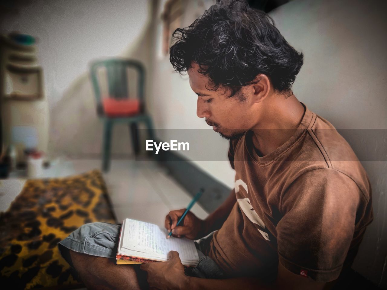 MAN HOLDING BOOK WHILE SITTING ON TABLE