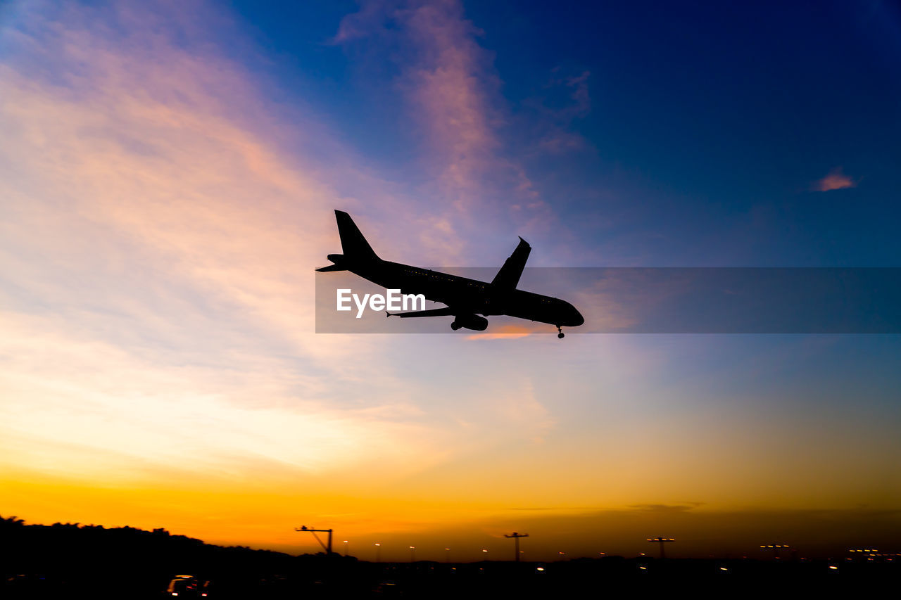 Low angle view of silhouette airplane flying against sky during sunset