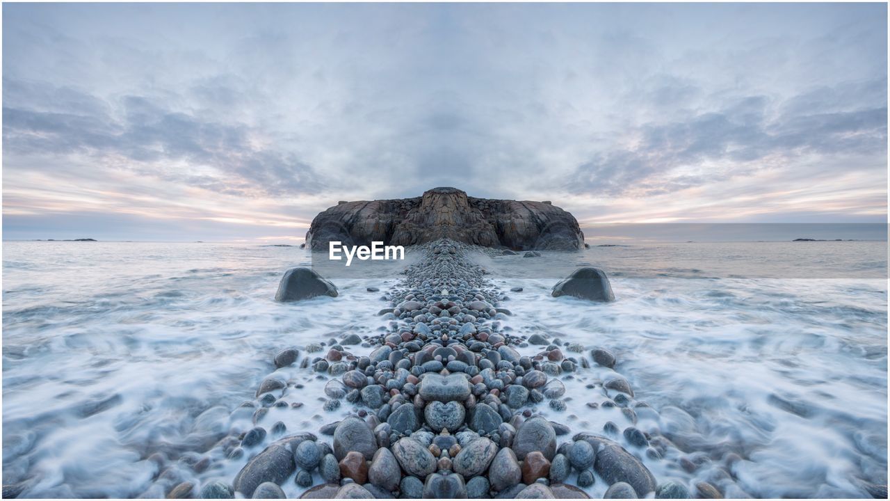 Digital composite image of rocks in sea against sky