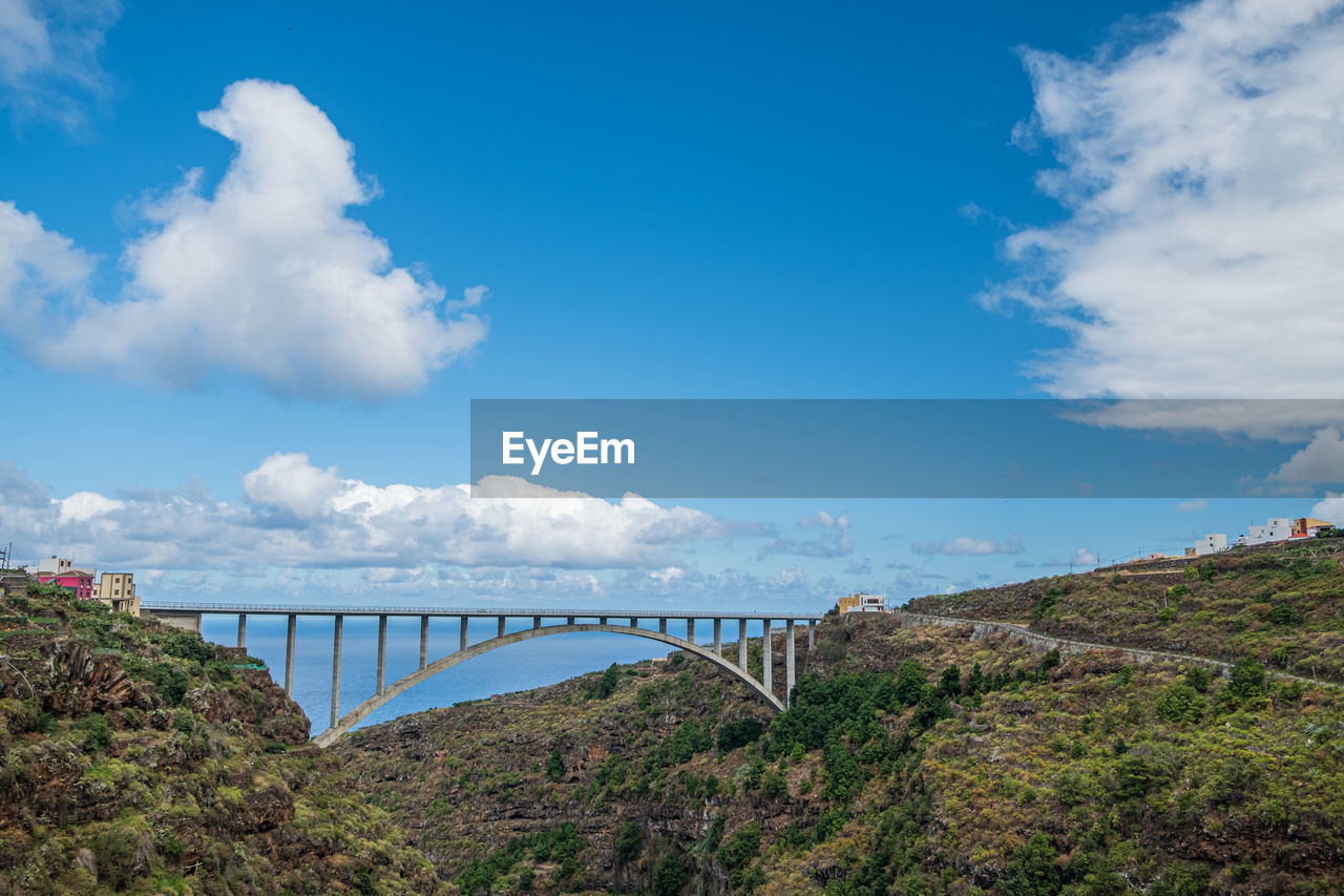 Bridge over the valley with blue sky and sea in the background