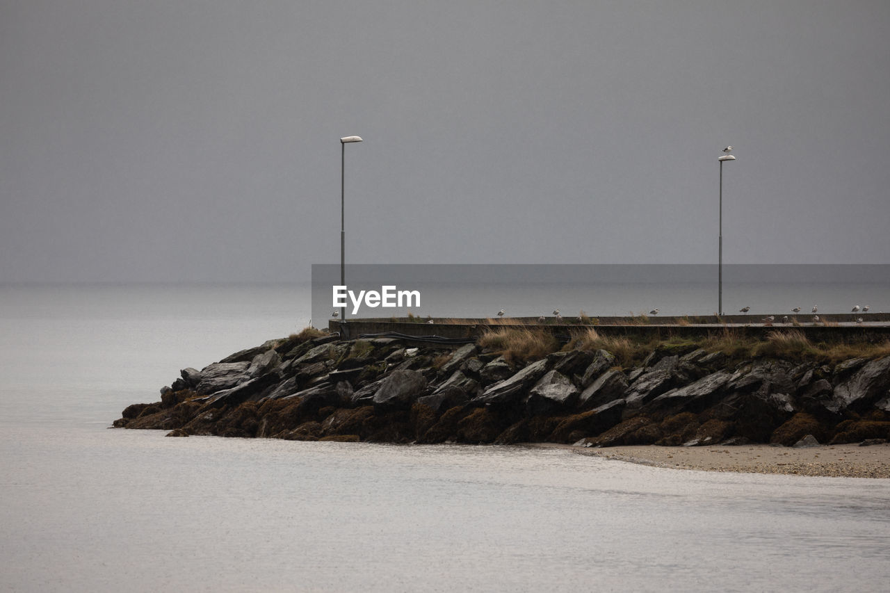 Rock formations by sea against clear sky