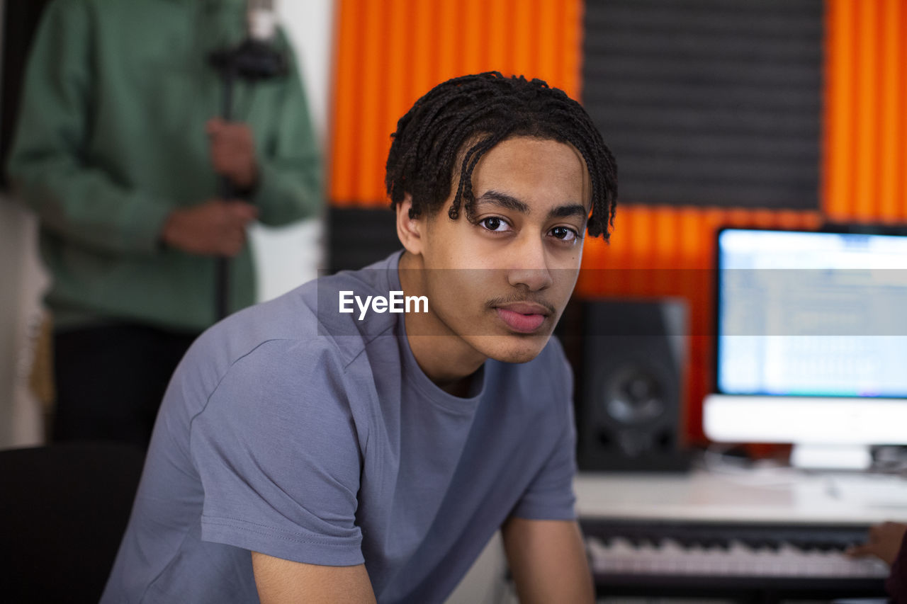 Side view of boy with dreads sitting in recording studio