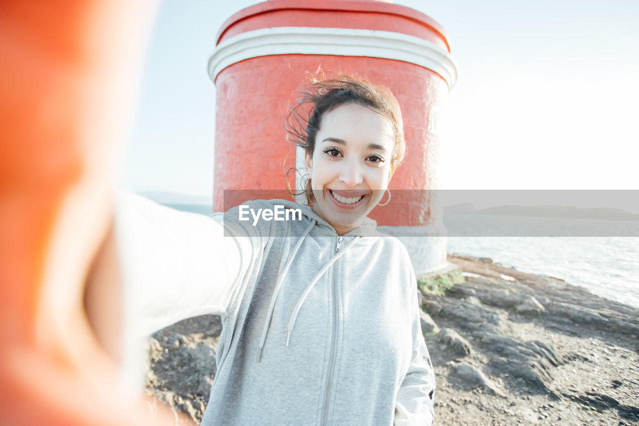 Portrait of young woman standing at beach