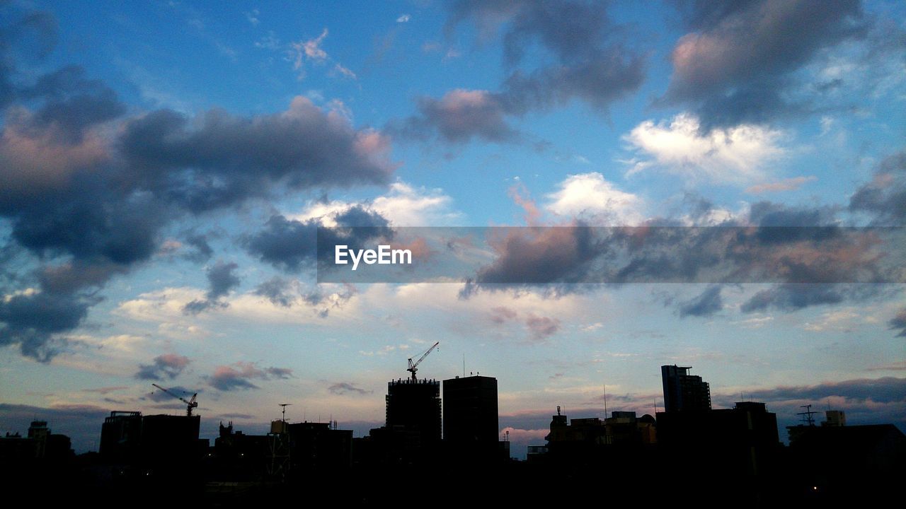 LOW ANGLE VIEW OF BUILDINGS IN CITY AGAINST CLOUDY SKY