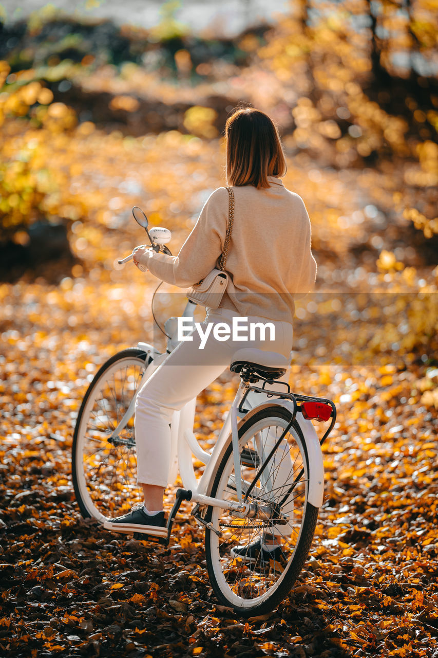 Rear view of woman with bicycle during autumn