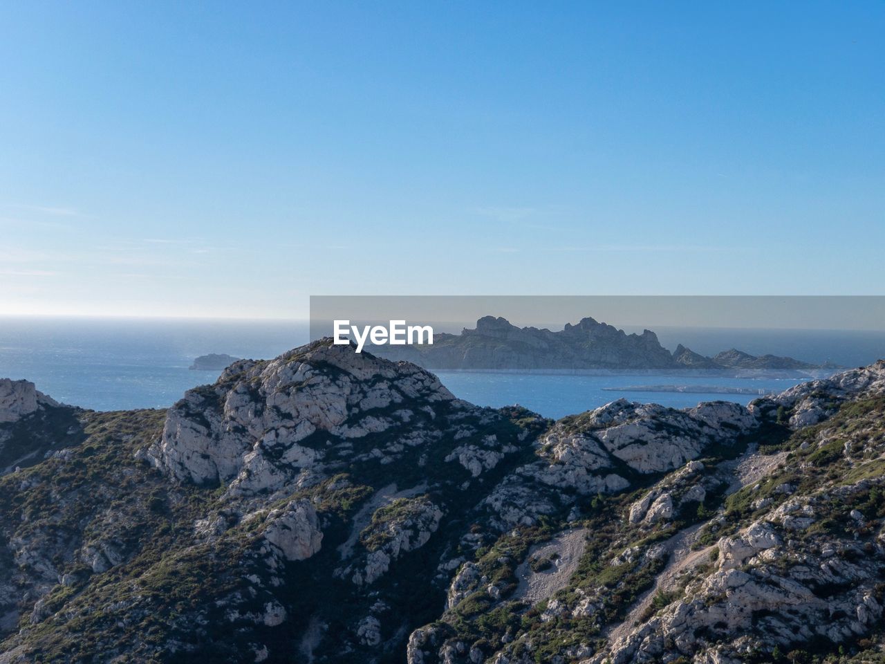 Scenic view of sea and mountains against blue sky