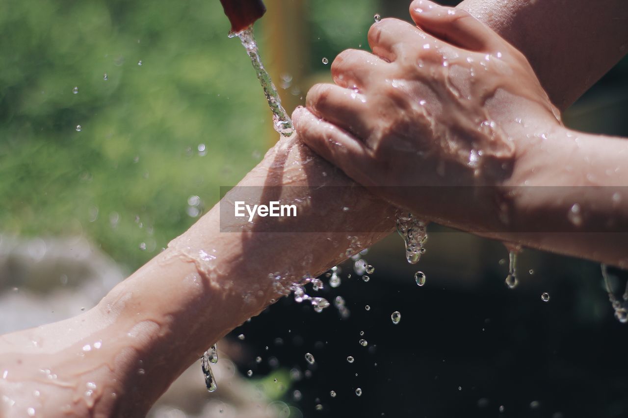 CLOSE-UP OF WATER DROPS ON WOMAN WITH HANDS