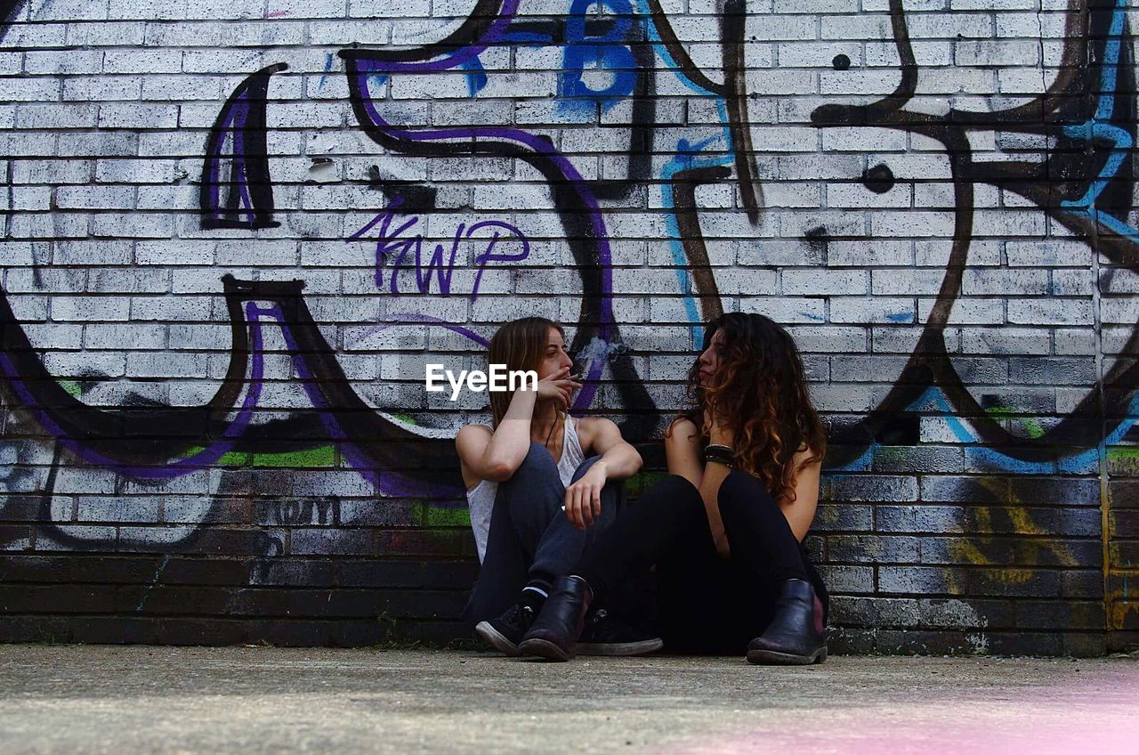 YOUNG WOMAN SITTING ON WALL