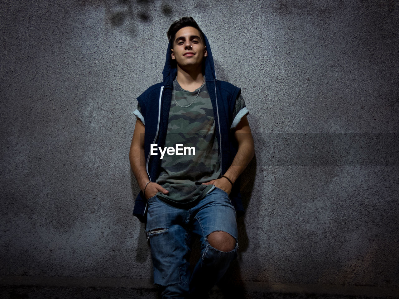 Portrait of confident young man standing against wall