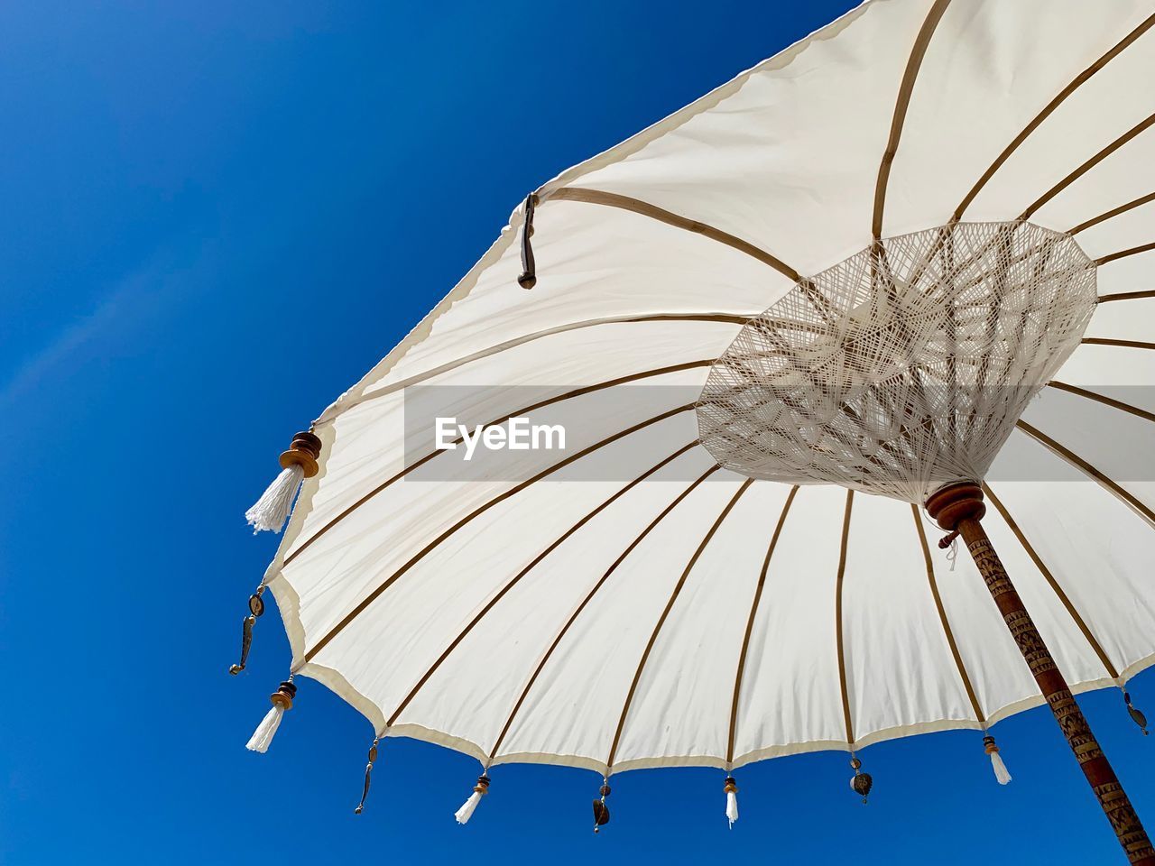 Low angle view of umbrella against clear blue sky