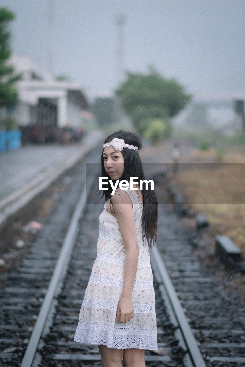 Portrait of woman standing on railroad track