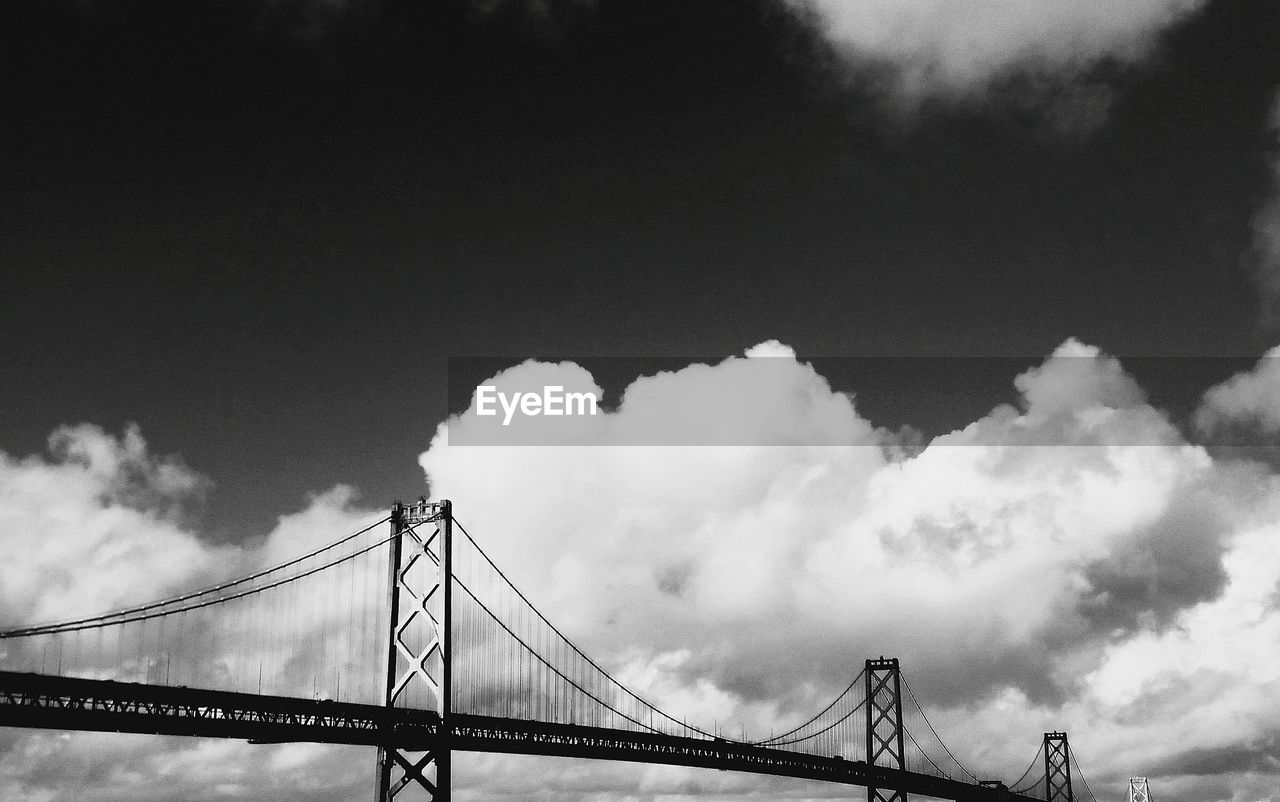 Low angle view of bay bridge against cloudy sky