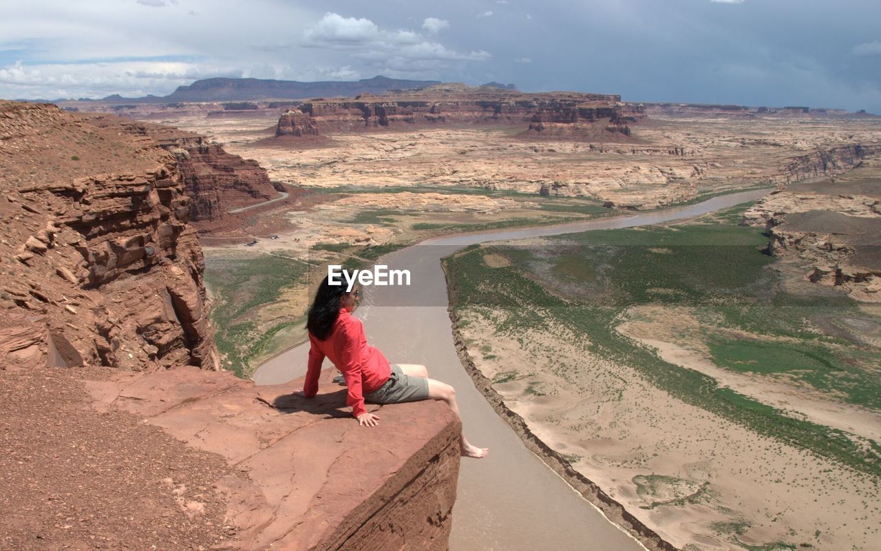 High angle view of woman sitting on cliff at desert