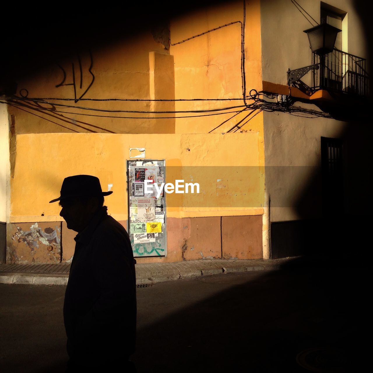 Side view of silhouette man walking on street during sunny day