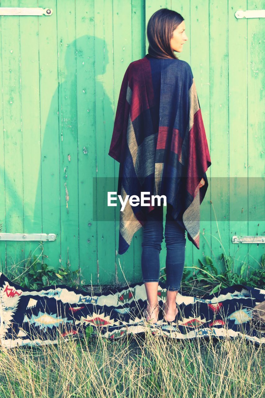 Woman standing on blanket by log cabin