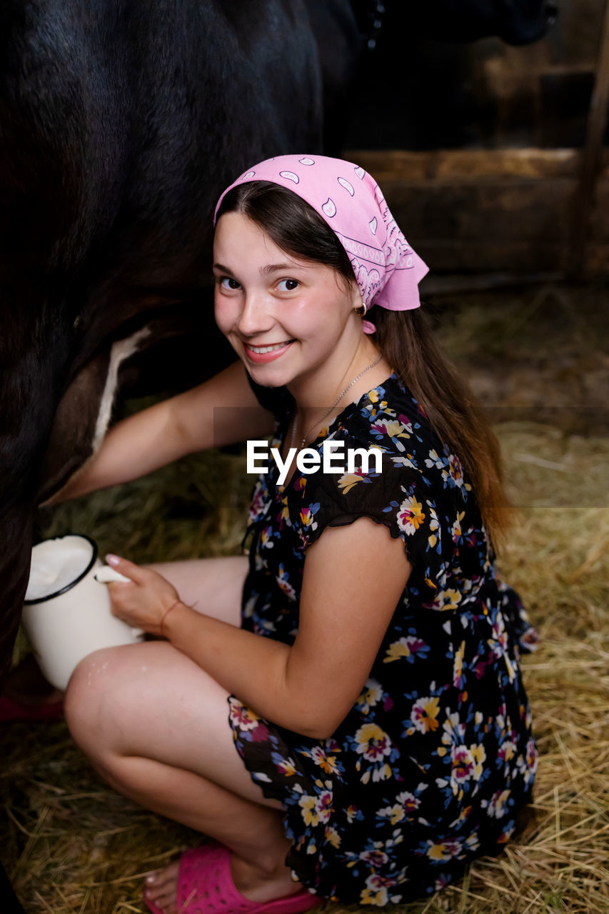 Cute ukrainian girl milk a cow in countryside