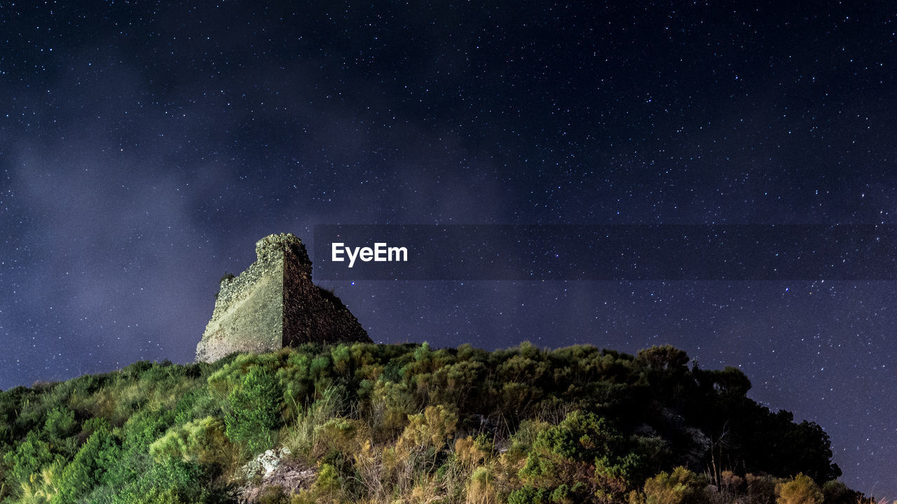 Low angle view of old ruin on mountain against star field at night