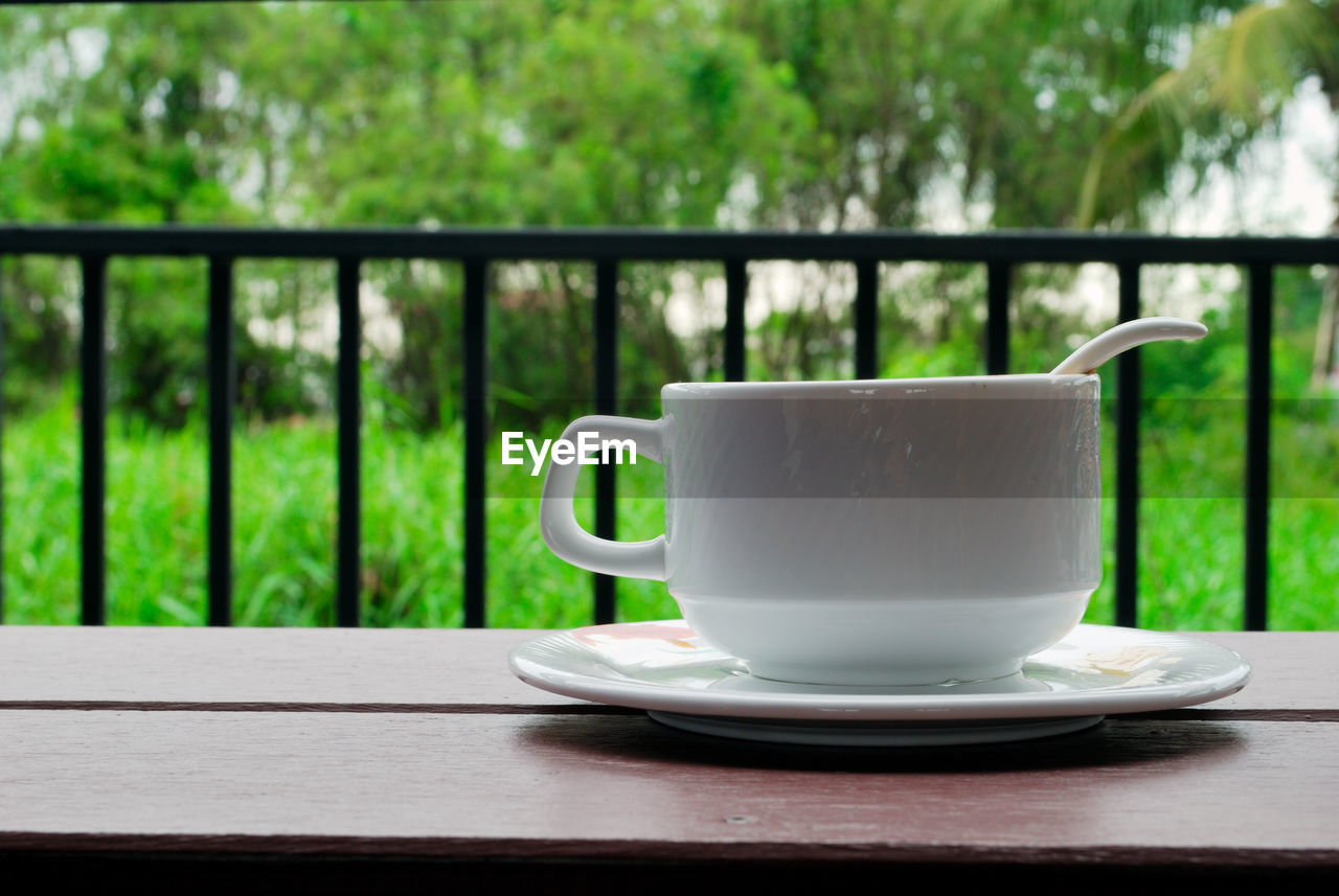 CLOSE-UP OF COFFEE ON TABLE AGAINST RAILING