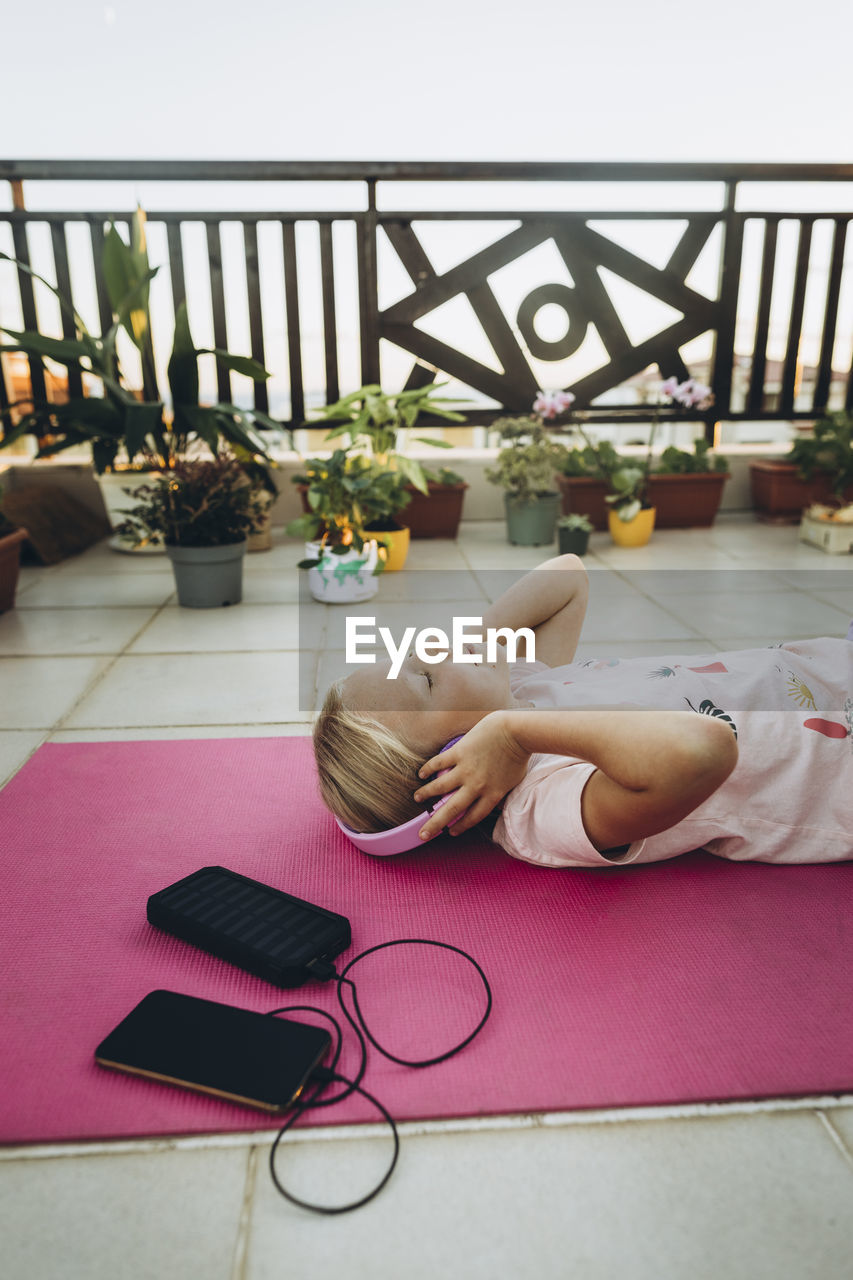 Girl listening to music with headphones lying on terrace