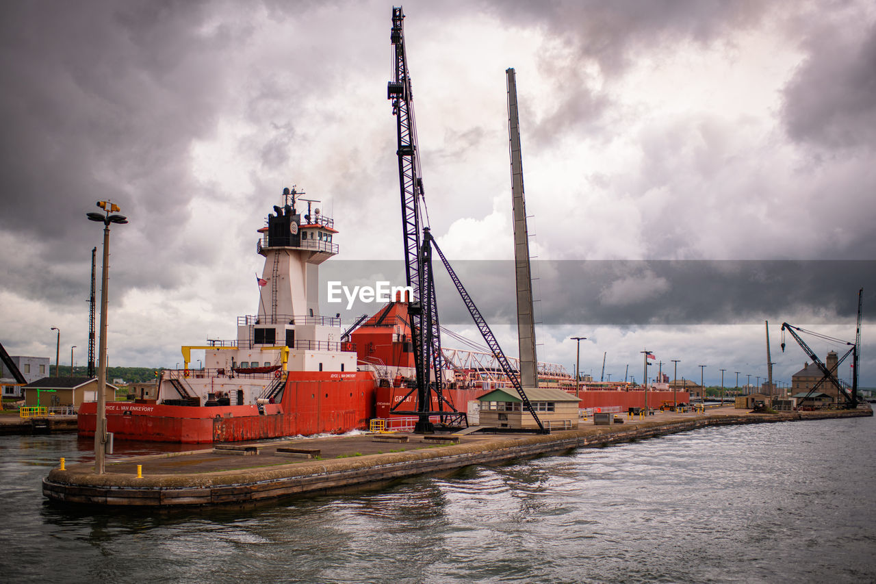 VIEW OF COMMERCIAL DOCK AGAINST CLOUDY SKY