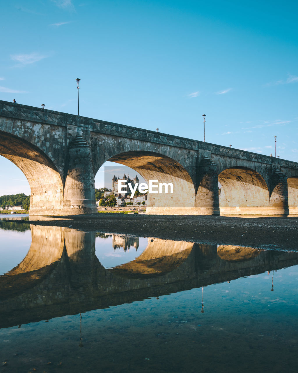 Arch bridge over river against clear blue sky