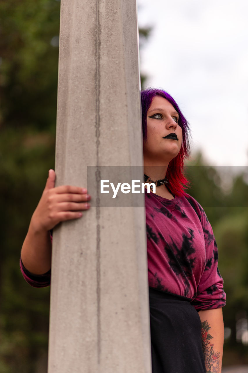 Portrait of young woman standing against lamppost 