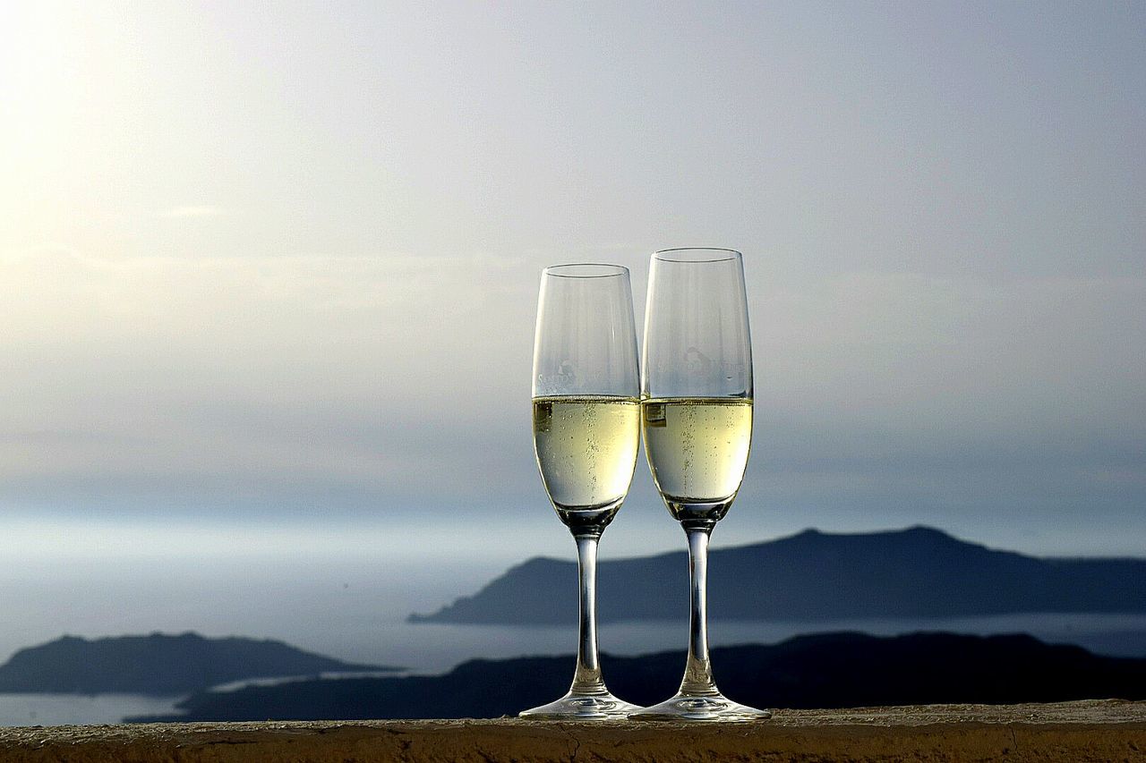 Champagne flutes on retaining wall against sky