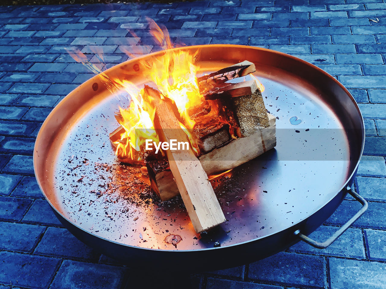 HIGH ANGLE VIEW OF FIRE IN CONTAINER ON TABLE