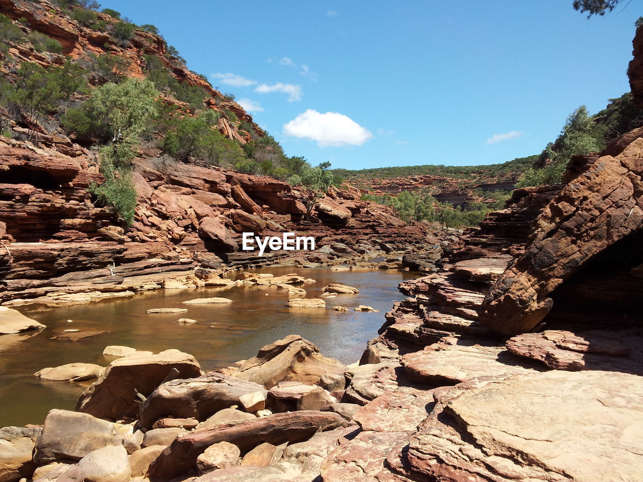 Pond amidst rocky mountains against sky