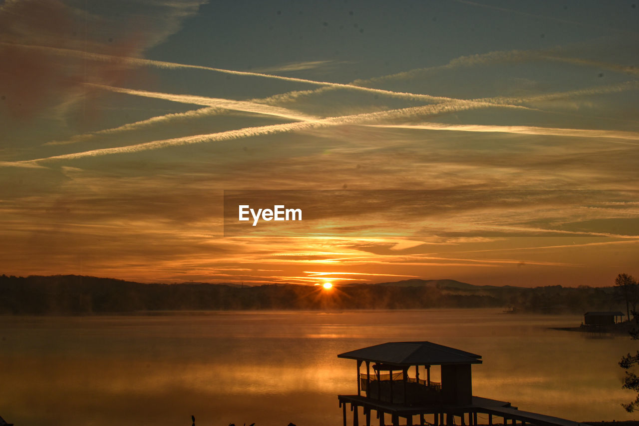 Silhouette of dock against sky during sunrise