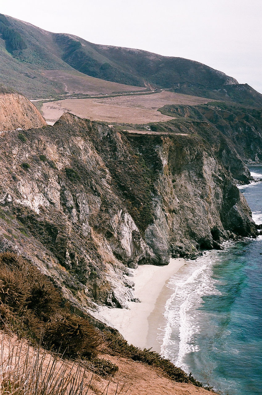 Cliff by sea against sky