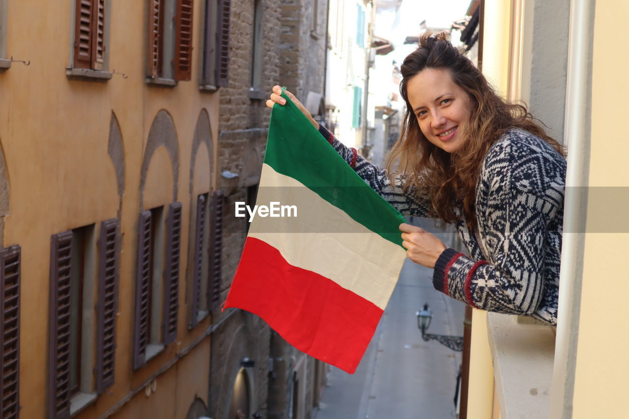 Portrait of woman holding flag while standing in balcony