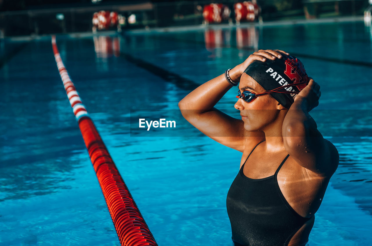 MIDSECTION OF WOMAN SWIMMING IN POOL AT NIGHT