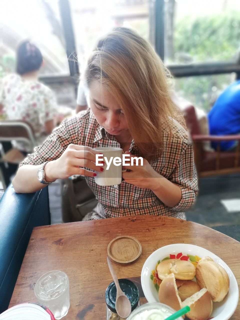 Woman drinking coffee while sitting at table in restaurant