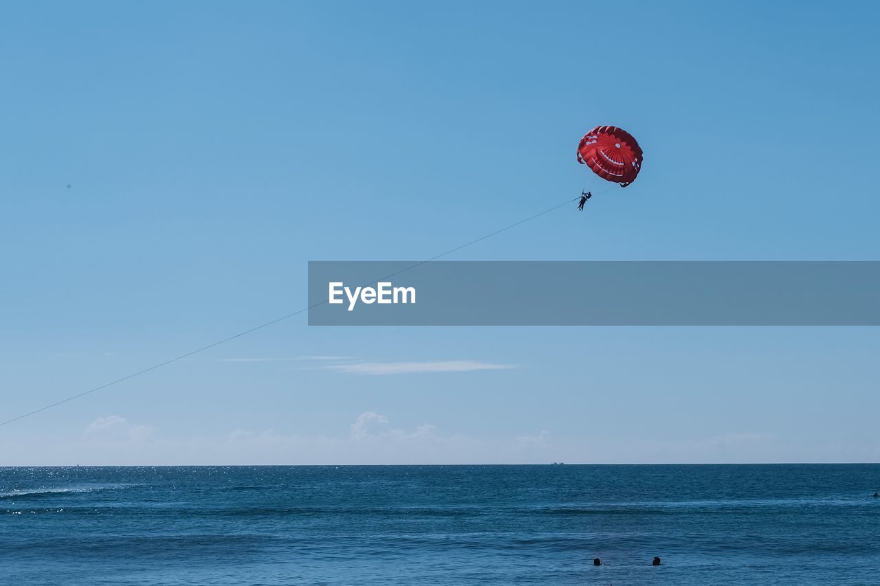 Man paragliding over sea against sky