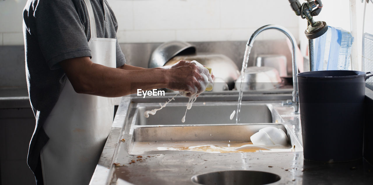 MIDSECTION OF MAN PREPARING FOOD AT HOME