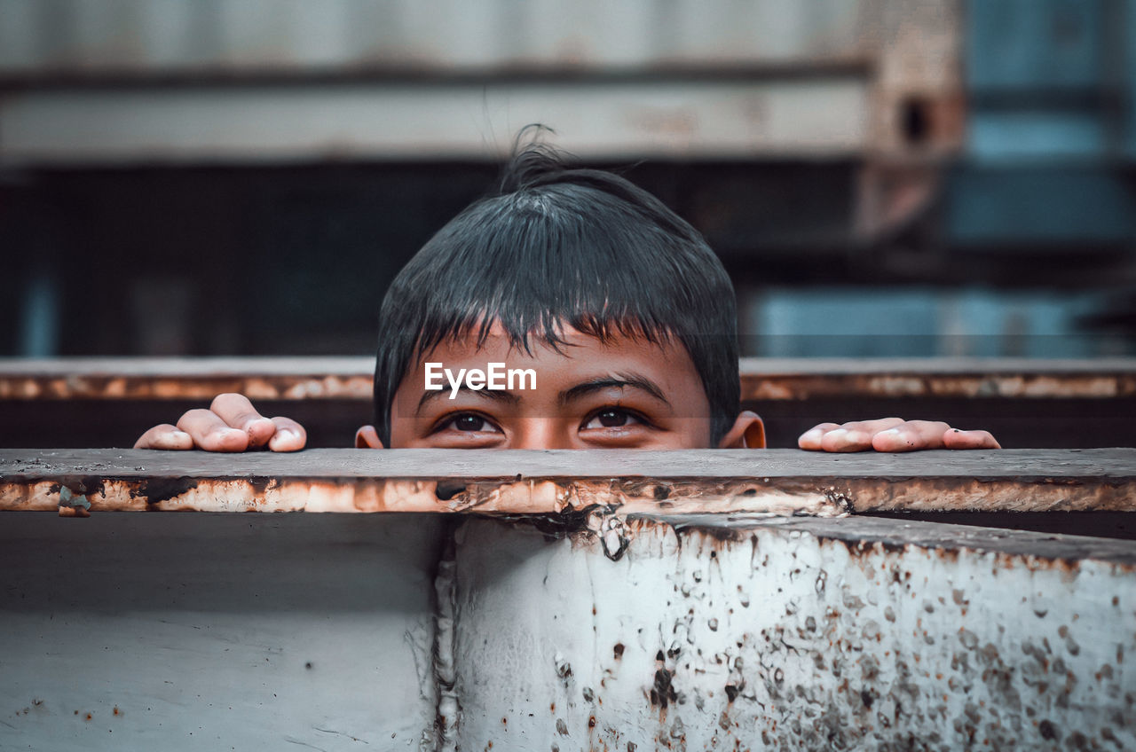 Close-up portrait of boy with metal fence