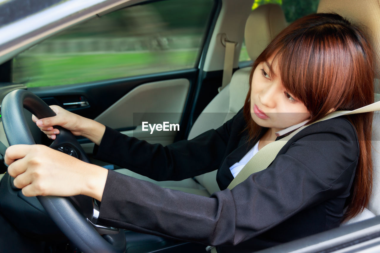 Businesswoman talking on phone while driving car