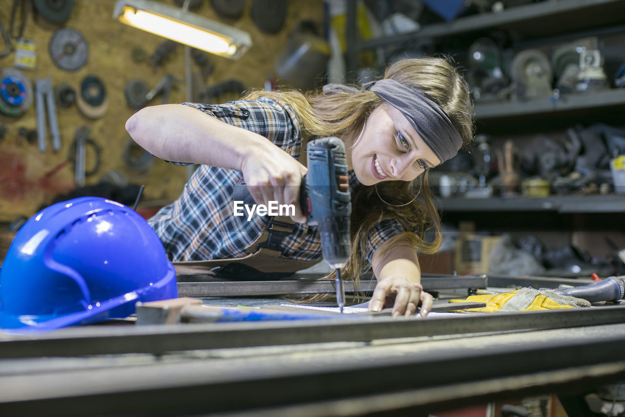 Woman using drill in workshop