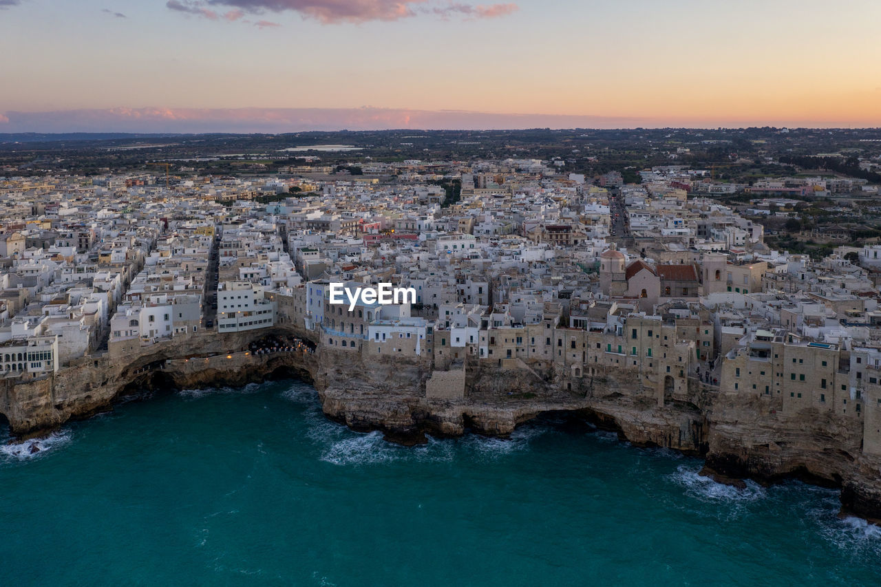 High angle view of townscape by sea against sky during sunset