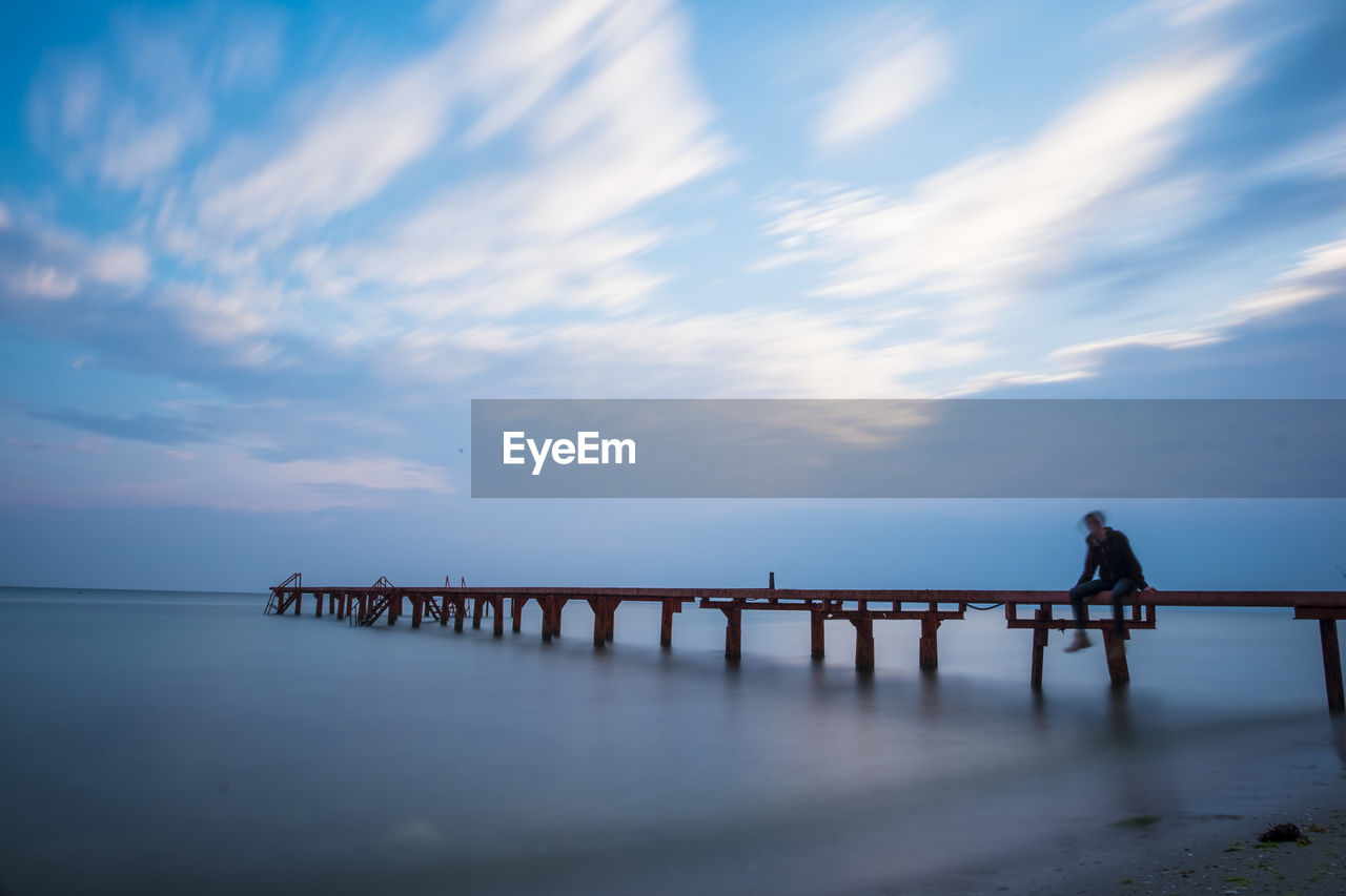 SILHOUETTE WOMAN STANDING ON PIER OVER SEA AGAINST SKY