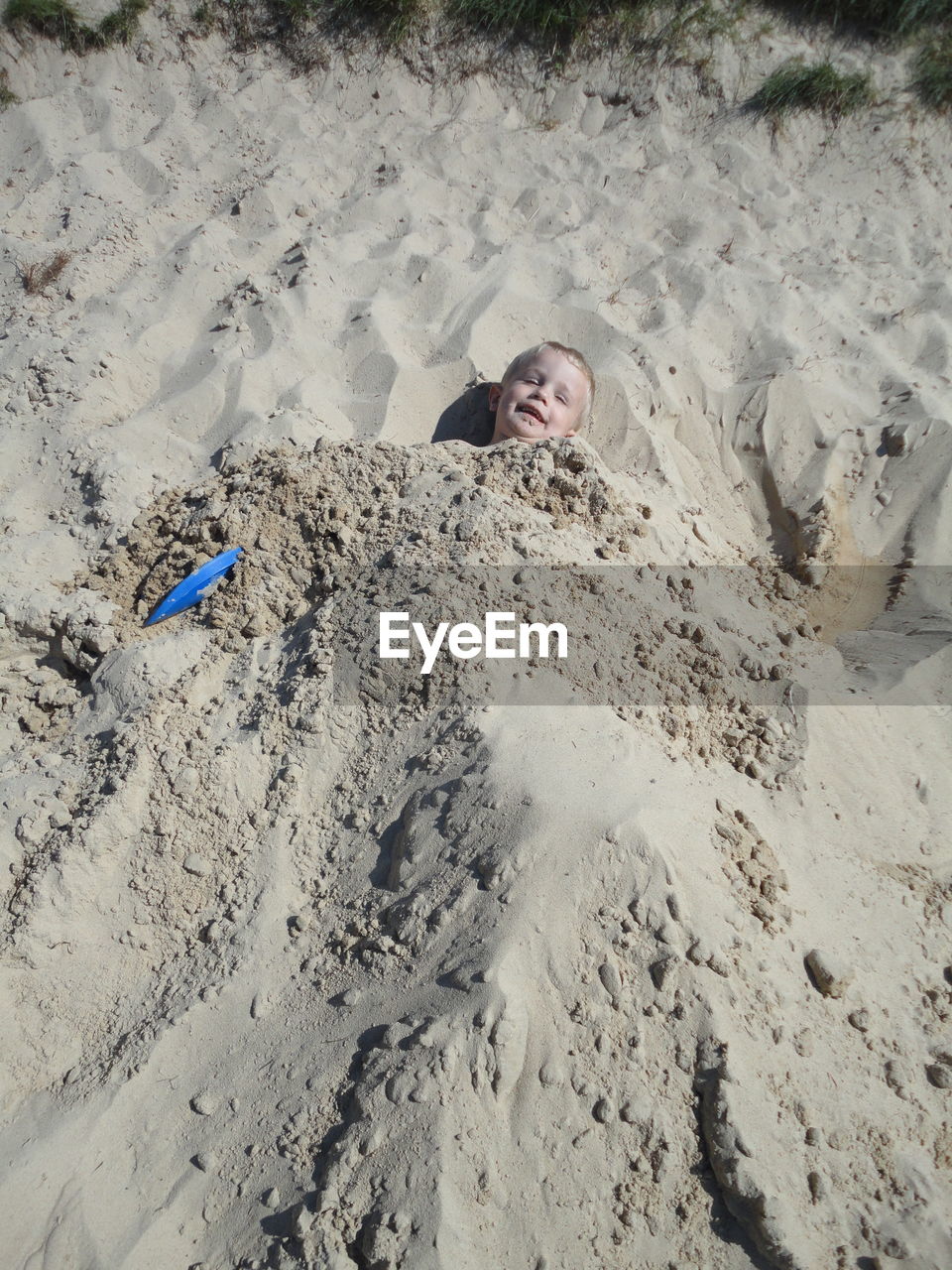 High angle view of boy covered with sand at beach