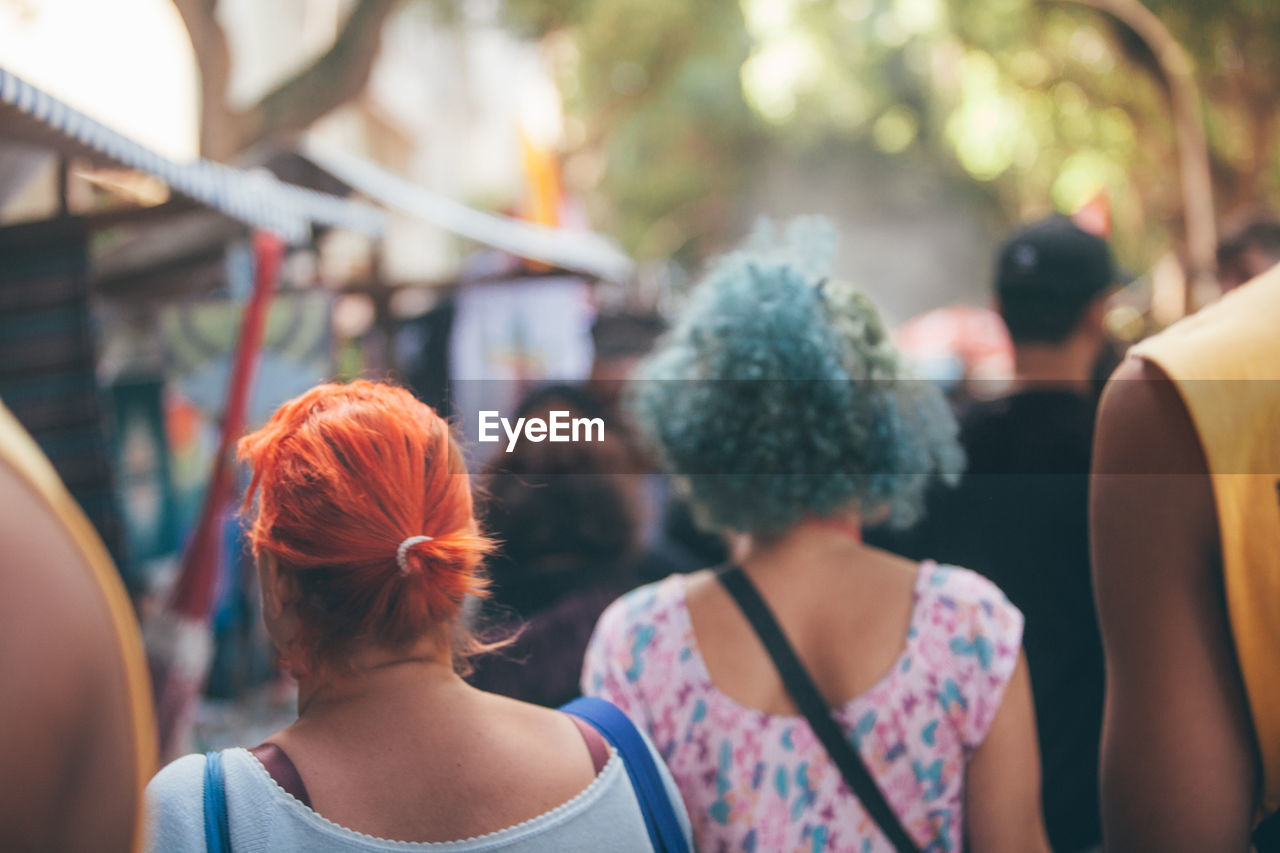 Two women with red and blue hair walking in a market