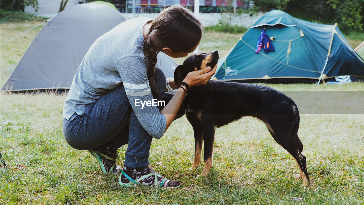 Woman playing with dog on grassy land at campsite