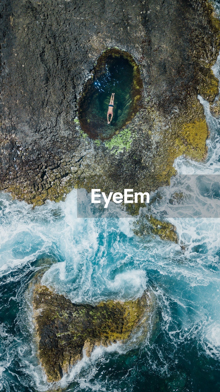 Drone view of man swimming in tidal pool