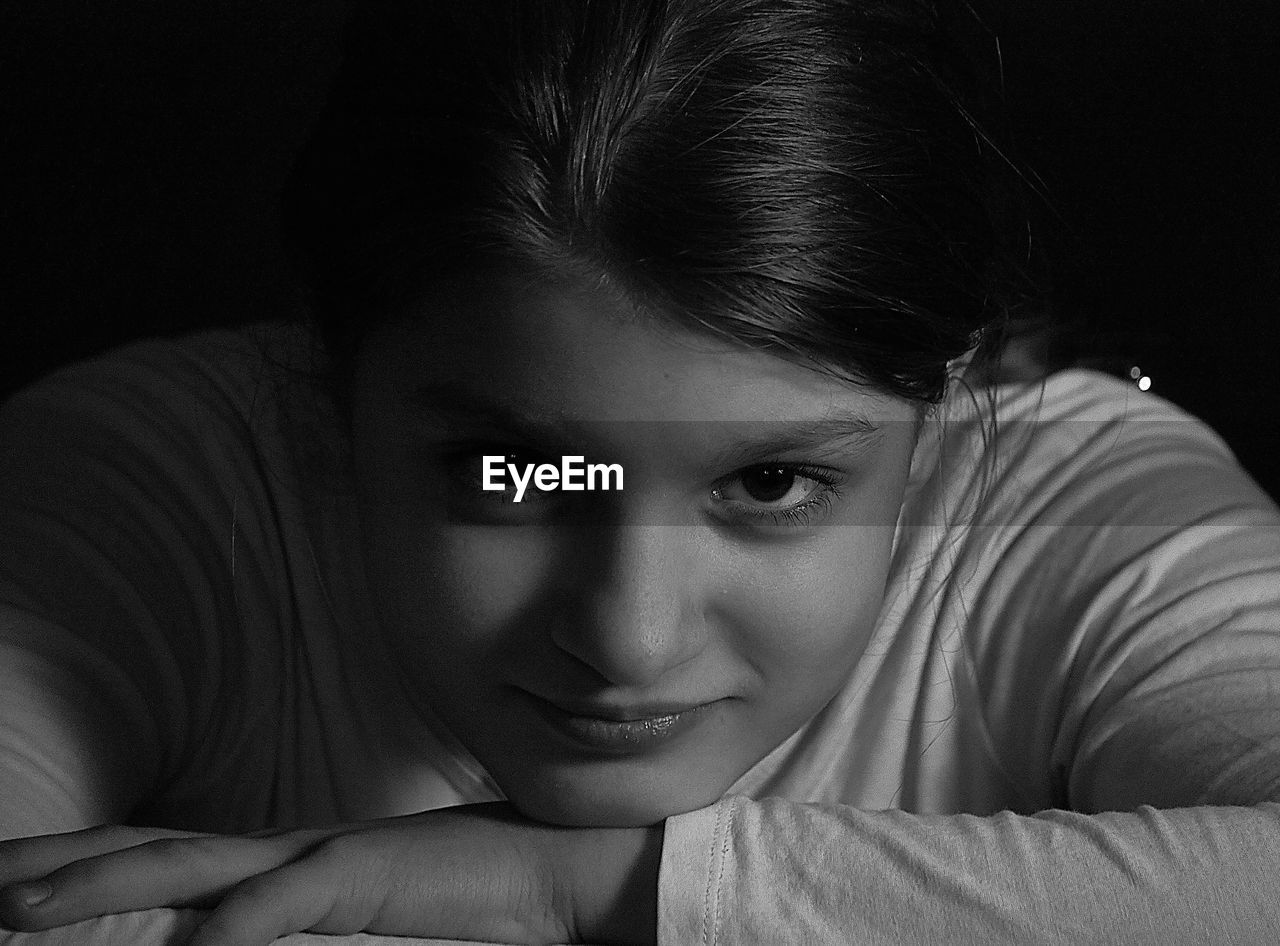 Close-up portrait of girl smiling against black background