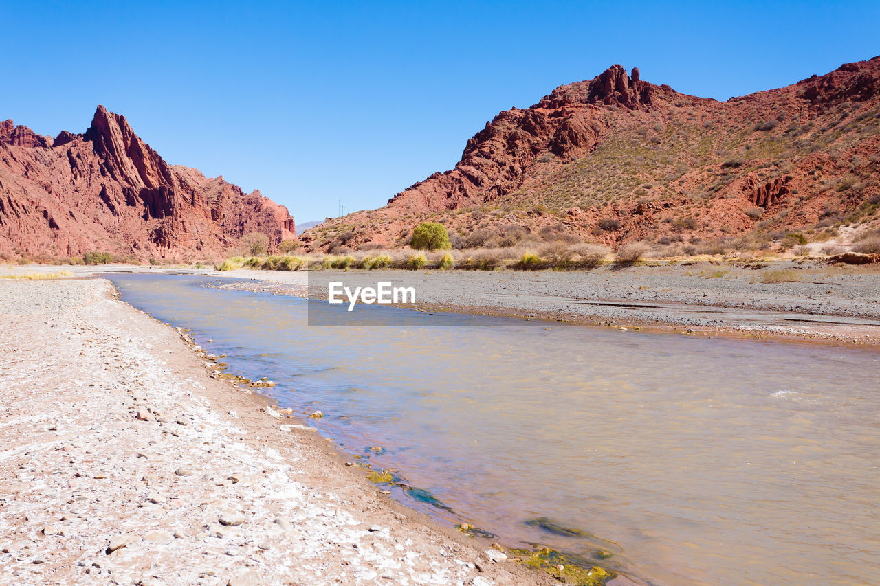 landscape, scenics - nature, environment, land, sky, nature, water, mountain, beauty in nature, travel destinations, desert, clear sky, travel, wadi, wilderness, rock, blue, sea, no people, semi-arid, valley, sunny, coast, geology, non-urban scene, natural environment, beach, sand, tranquility, shore, outdoors, animal wildlife, tourism, rock formation, mountain range, tranquil scene, day, plateau, body of water, plant, nature reserve, sunlight, arid climate, accidents and disasters, climate