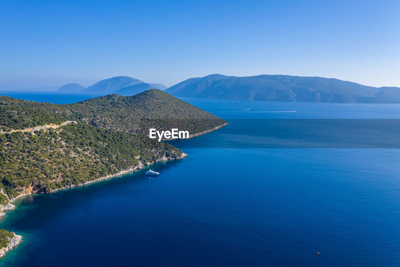 SCENIC VIEW OF SEA AND MOUNTAINS AGAINST BLUE SKY